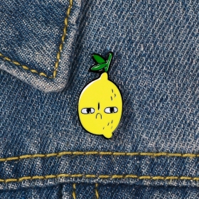 Желтого цвета пин с изображением грустного лимончика