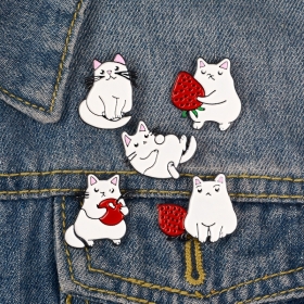 Белые коты играют с красным яблоком и ягодами значки