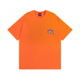 Оранжевая футболка бренда STUSSY с клетчатым логотипом