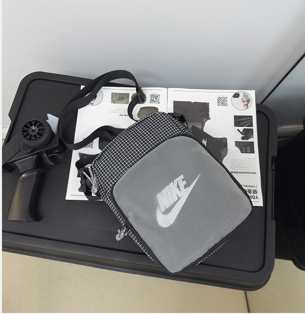 Серая барсетка Nike выполнена из плотного текстиля в клетку