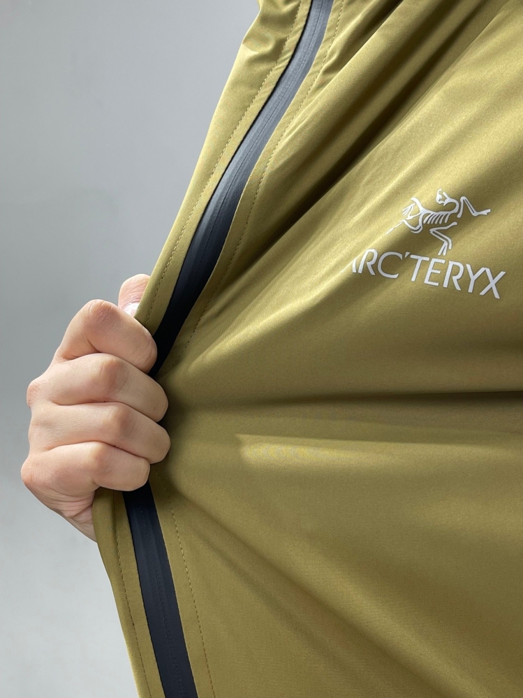 Горчичная куртка Arcteryx с высоким воротником и логотипом на груди