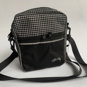 Чёрная в клетку сумка-барсетка с лого Stussy выполнена из полиэстера